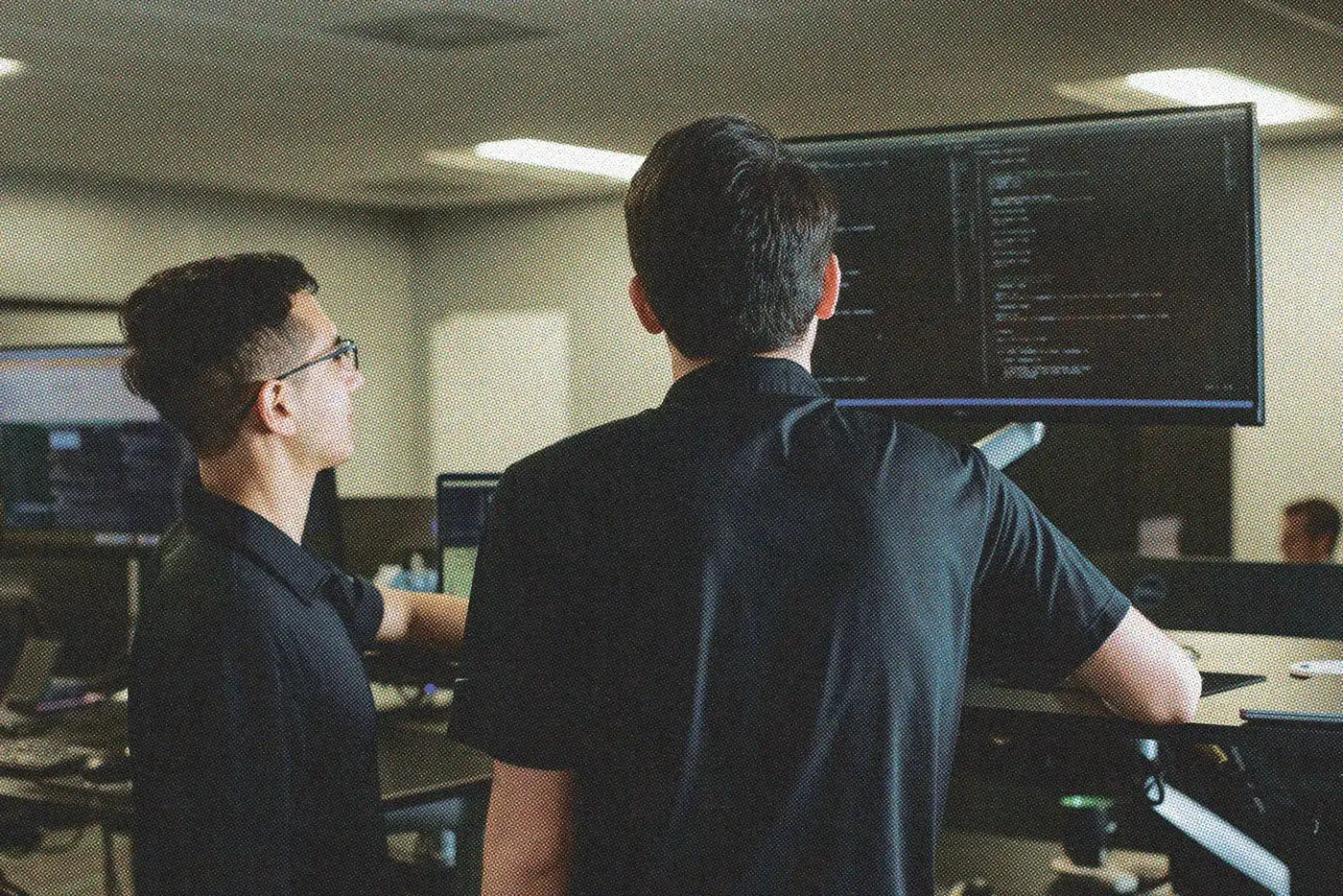 Two engineers reviewing code together on a wall display