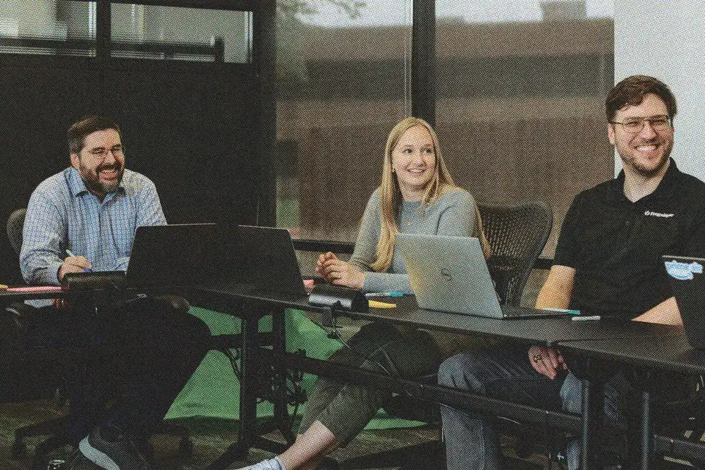 Three teammates working together at laptops